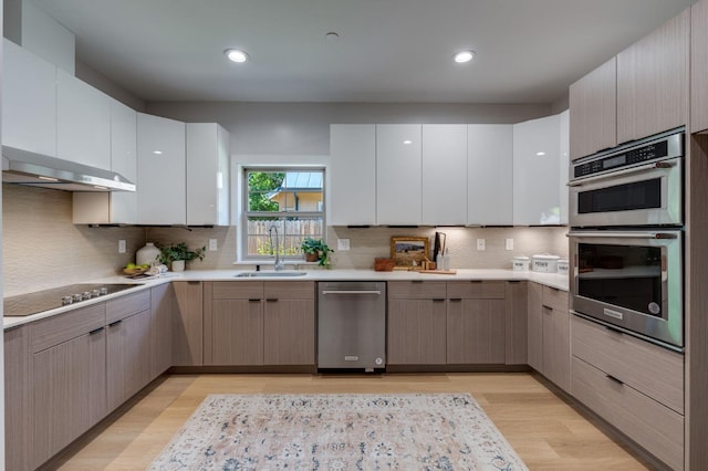 kitchen featuring light countertops, a sink, appliances with stainless steel finishes, and light wood-style flooring
