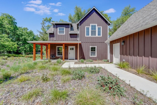 view of front of house with board and batten siding, roof with shingles, covered porch, and driveway