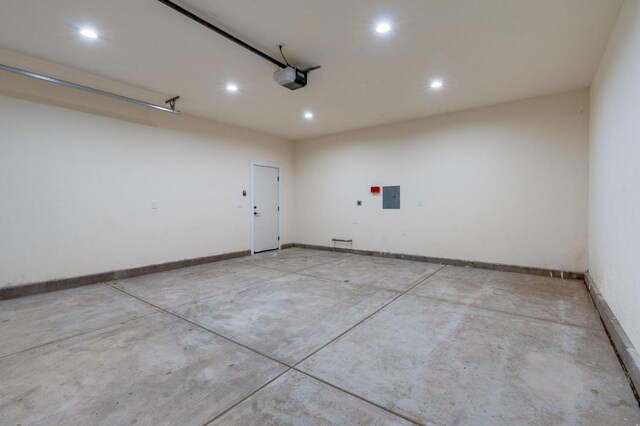 garage featuring electric panel, baseboards, recessed lighting, and a garage door opener