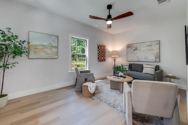 living room featuring wood finished floors, visible vents, a ceiling fan, and baseboards