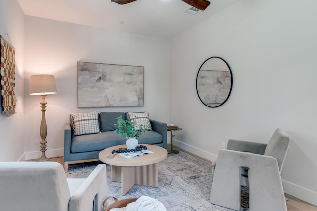 living room featuring ceiling fan, baseboards, and wood finished floors