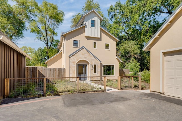 view of front of property with a garage, aphalt driveway, stucco siding, and fence