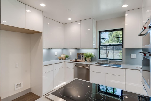 kitchen with black electric cooktop, dishwasher, a sink, modern cabinets, and white cabinetry
