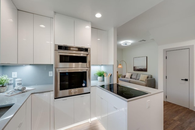 kitchen featuring double oven, modern cabinets, black electric stovetop, white cabinets, and a peninsula