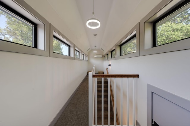 hallway with a wall mounted AC, vaulted ceiling, and carpet flooring