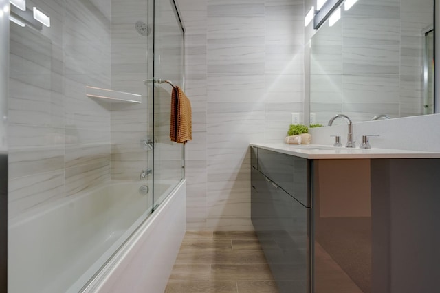 bathroom featuring tile walls, combined bath / shower with glass door, and vanity