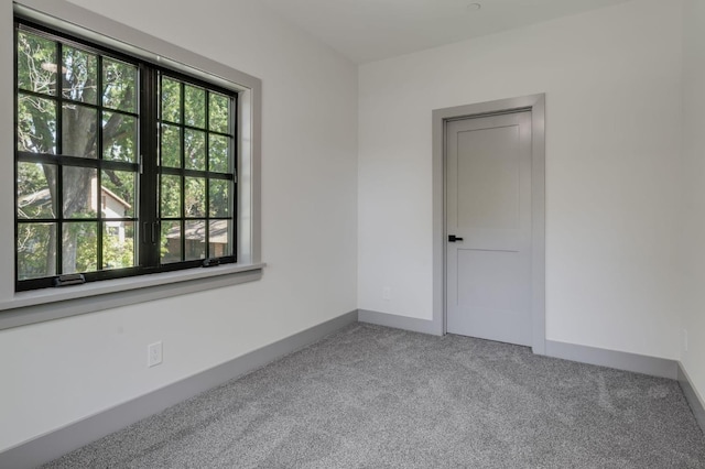 carpeted empty room featuring baseboards