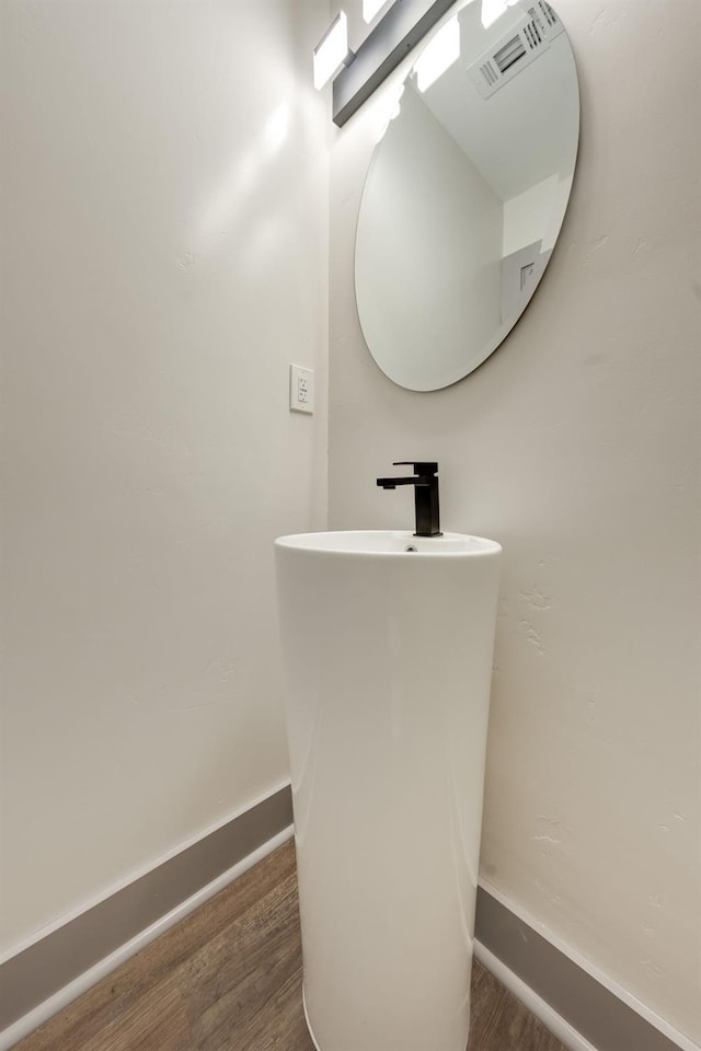 bathroom with wood finished floors, visible vents, baseboards, and a sink