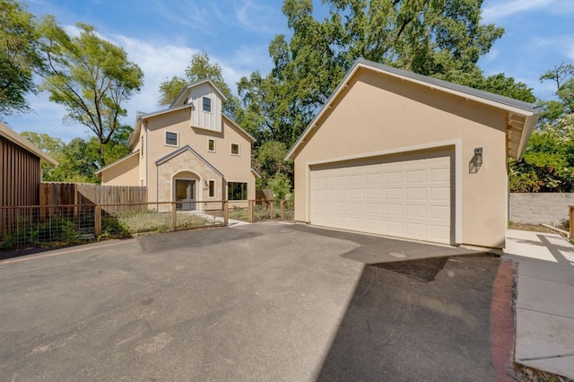 view of front facade with stucco siding, an outdoor structure, fence, and a detached garage