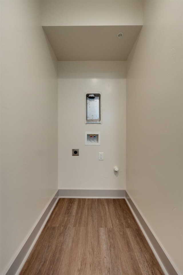 clothes washing area with wood finished floors, electric dryer hookup, baseboards, laundry area, and washer hookup