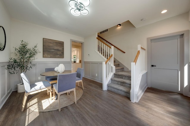 dining area with stairway, wood finished floors, wainscoting, a notable chandelier, and visible vents