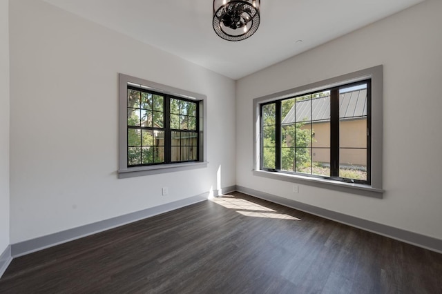 empty room featuring dark wood-type flooring, plenty of natural light, and baseboards