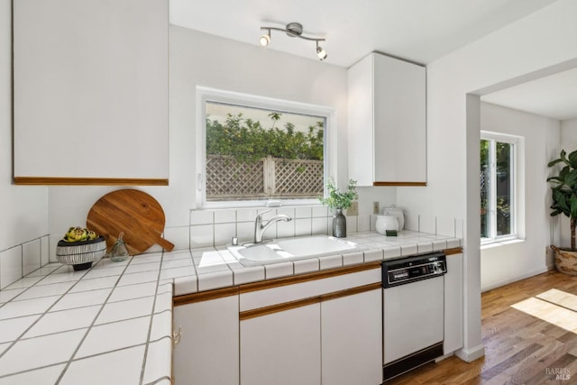 kitchen featuring white cabinetry, white dishwasher, a sink, and light wood-style floors