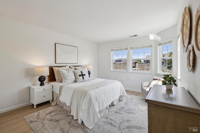 bedroom with light wood-style floors, visible vents, and baseboards