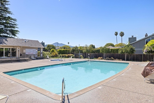 community pool with fence, a patio area, and a mountain view