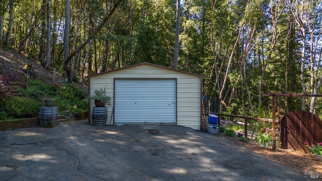 detached garage featuring a forest view and aphalt driveway