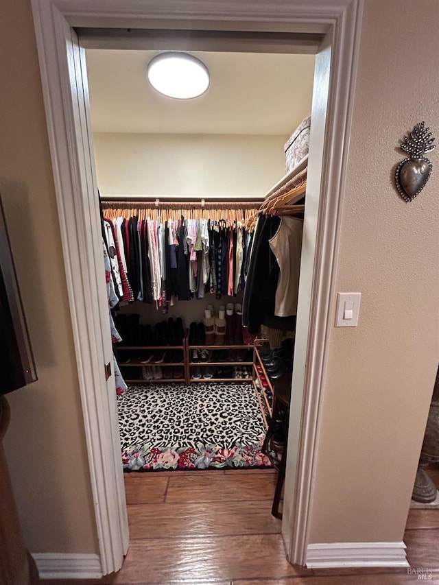 walk in closet with wood finished floors