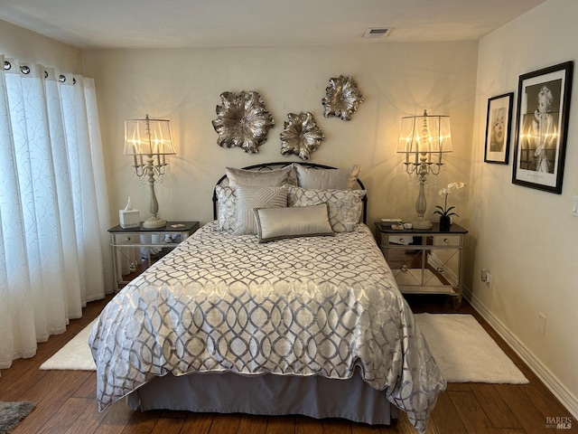 bedroom featuring dark wood finished floors, visible vents, and baseboards