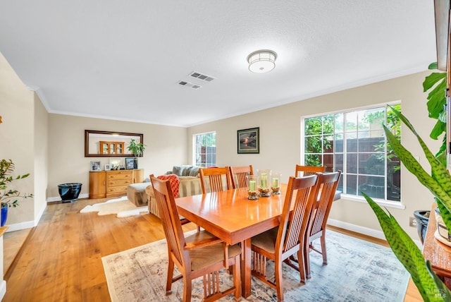 dining space with crown molding, light wood finished floors, visible vents, and baseboards