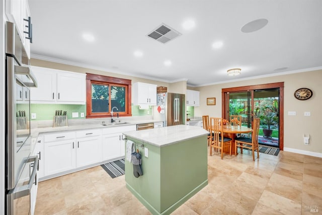 kitchen featuring white cabinets, a sink, appliances with stainless steel finishes, visible vents, and ornamental molding