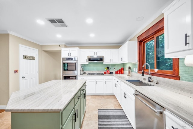 kitchen with green cabinetry, decorative backsplash, a sink, visible vents, and stainless steel appliances