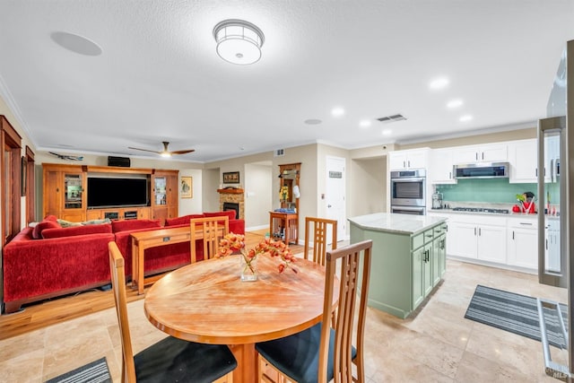 dining room featuring visible vents, ceiling fan, recessed lighting, ornamental molding, and a stone fireplace