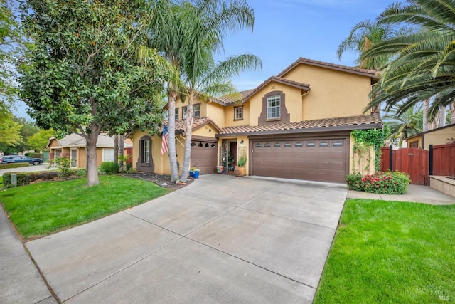 mediterranean / spanish house with stucco siding, fence, a front yard, concrete driveway, and an attached garage