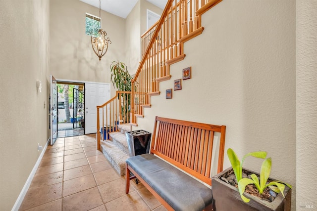 tiled entrance foyer with baseboards, a wealth of natural light, stairs, and a towering ceiling