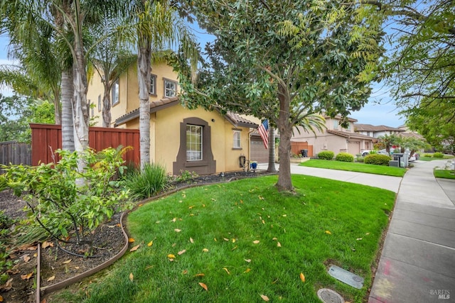 view of front of home featuring stucco siding, fence, and a front yard