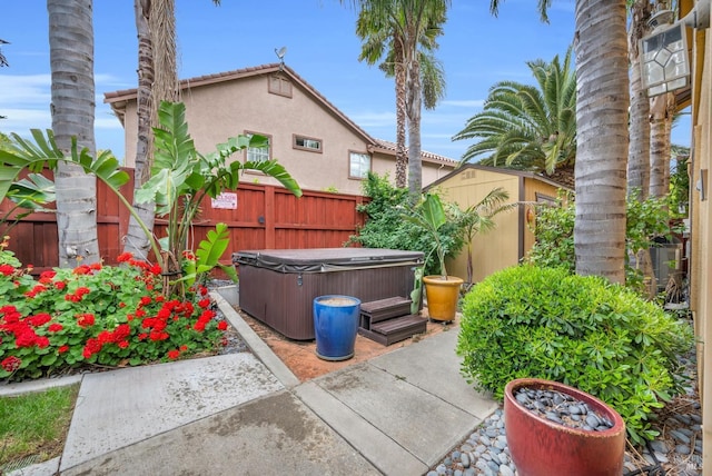 view of patio featuring a fenced backyard, a shed, a hot tub, and an outdoor structure