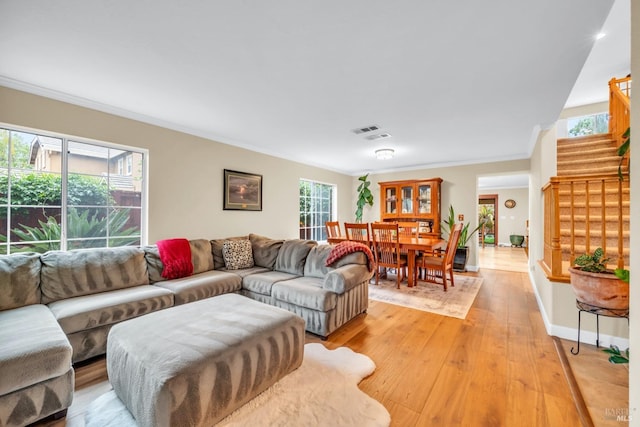 living area featuring ornamental molding, stairs, visible vents, and light wood-style floors
