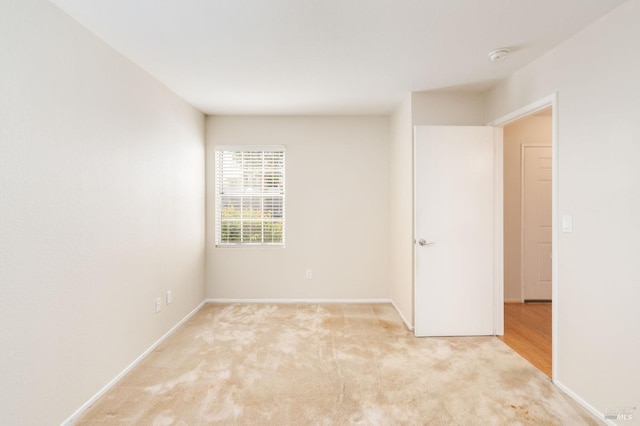 spare room with light colored carpet and baseboards