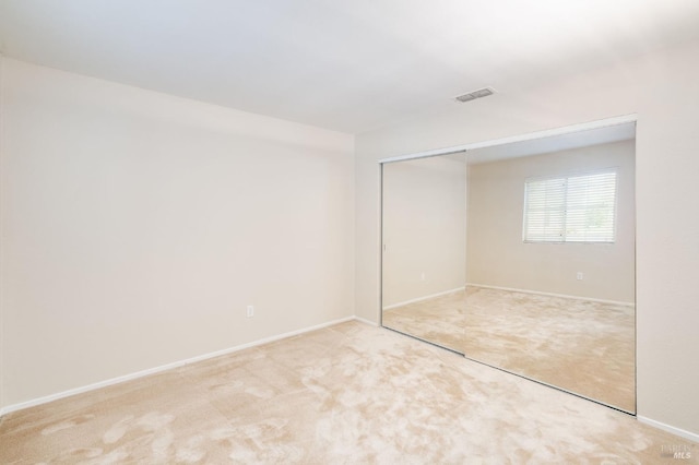 unfurnished bedroom with baseboards, carpet flooring, visible vents, and a closet