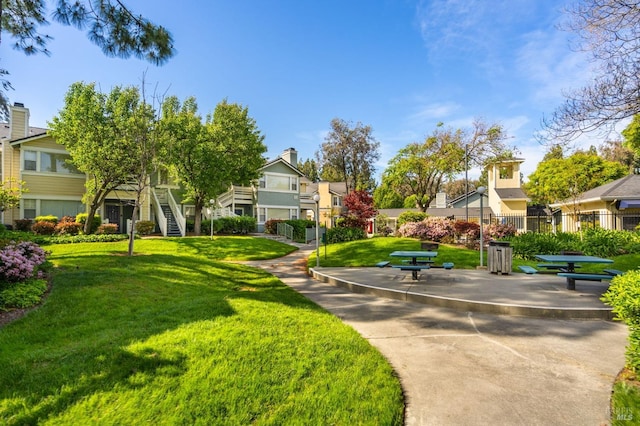 view of community featuring a yard, fence, and a residential view