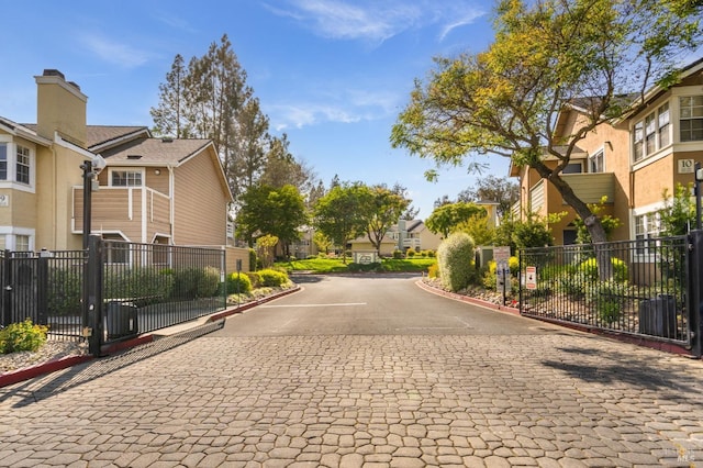 view of road with a residential view, curbs, and a gated entry