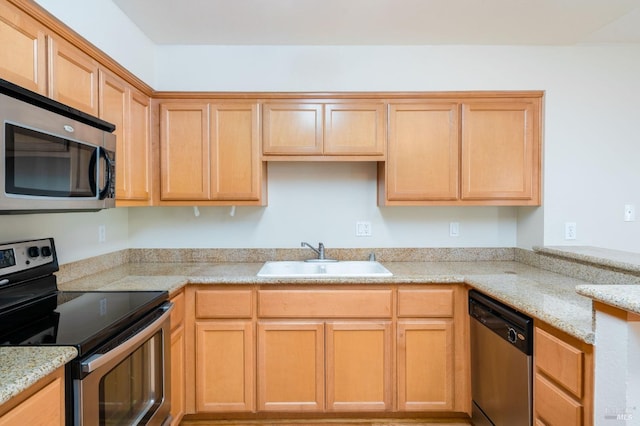 kitchen with light brown cabinets, a sink, a peninsula, appliances with stainless steel finishes, and light stone countertops