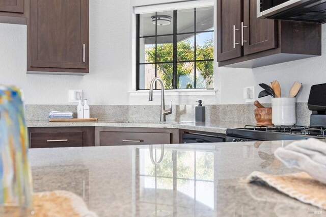kitchen featuring a sink, stainless steel appliances, a peninsula, and dark brown cabinets