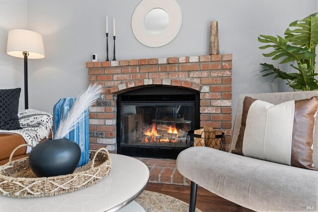 living area with visible vents, a brick fireplace, and wood finished floors