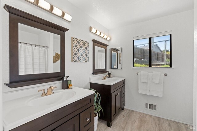 bedroom with baseboards, wood finished floors, lofted ceiling, visible vents, and a closet