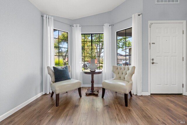 living area featuring wood finished floors, baseboards, lofted ceiling, and a wealth of natural light
