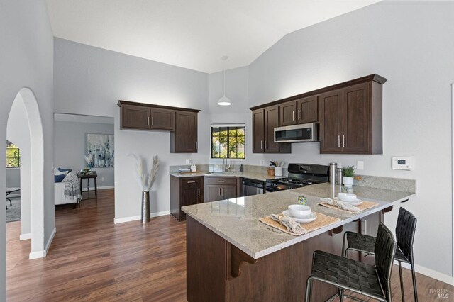kitchen with dark brown cabinetry, appliances with stainless steel finishes, a sink, high vaulted ceiling, and a peninsula
