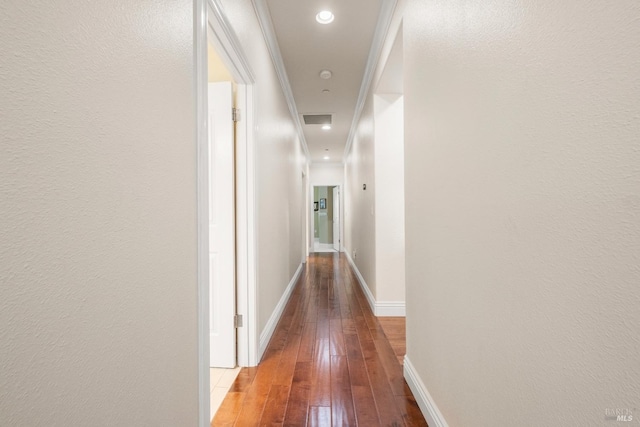 hallway featuring wood-type flooring, visible vents, and baseboards