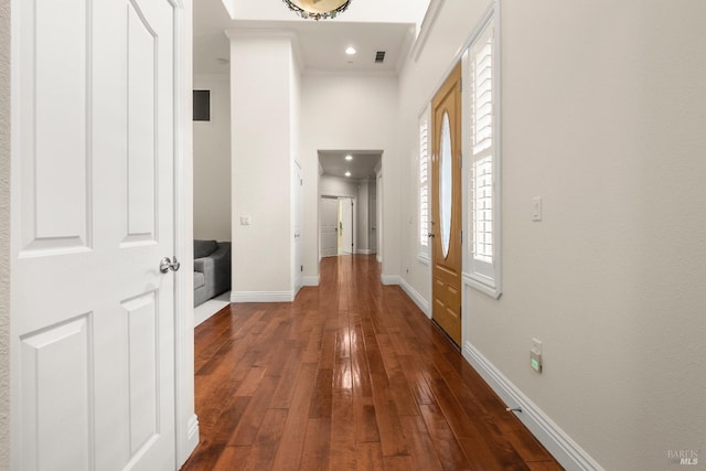 hallway featuring dark wood-style floors, baseboards, ornamental molding, visible vents, and recessed lighting