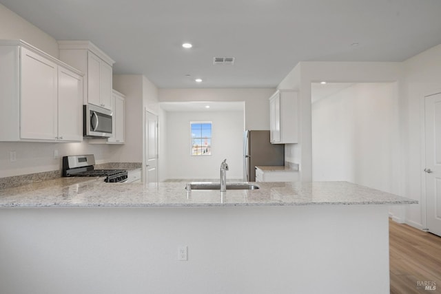 kitchen with light stone countertops, stainless steel appliances, visible vents, and a sink