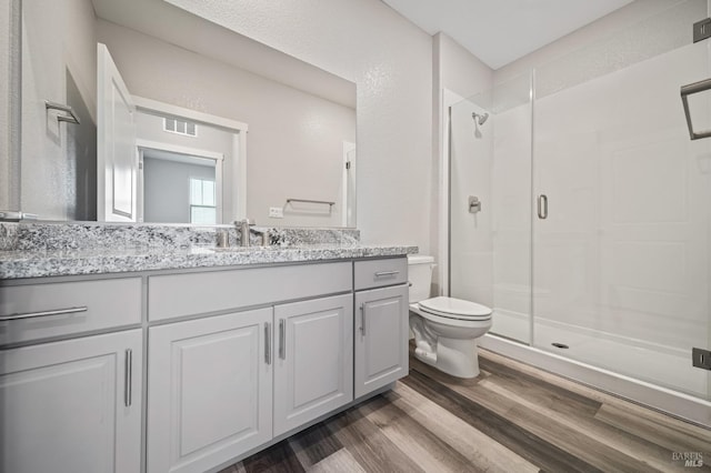 full bath featuring a shower stall, toilet, wood finished floors, and visible vents