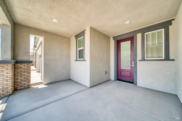 property entrance with stucco siding and a patio area