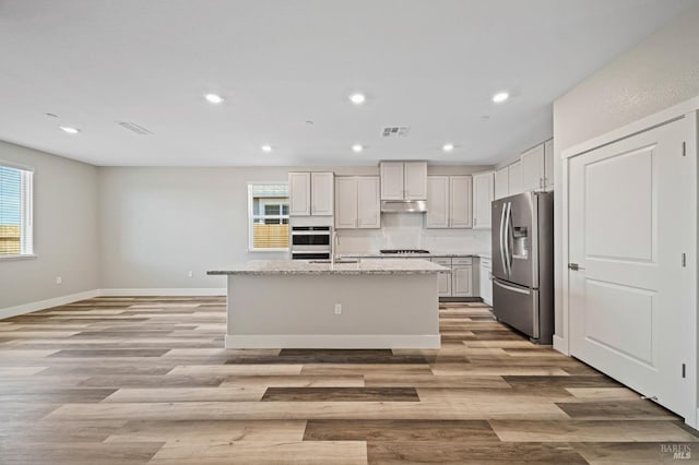 kitchen featuring visible vents, light wood-style floors, a healthy amount of sunlight, and stainless steel fridge with ice dispenser
