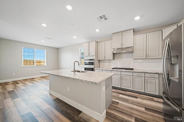 kitchen with stainless steel appliances, a sink, plenty of natural light, visible vents, and under cabinet range hood