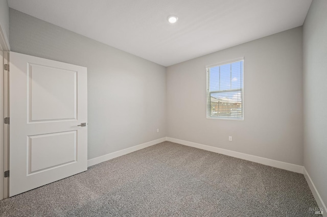 carpeted spare room featuring baseboards