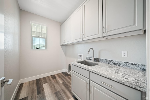 washroom featuring a sink, baseboards, hookup for a washing machine, cabinet space, and dark wood-type flooring